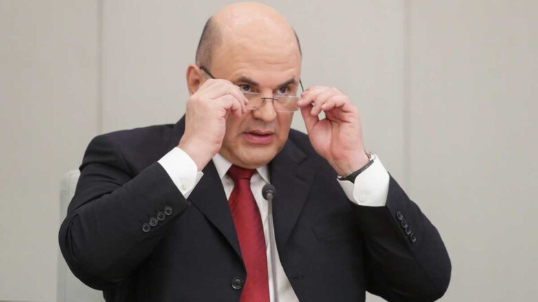 Михаил Мишустин держит руками очки