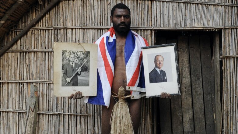 Сын вождя племени на острове Танна в Вануату держит официальные портреты принца Филиппа