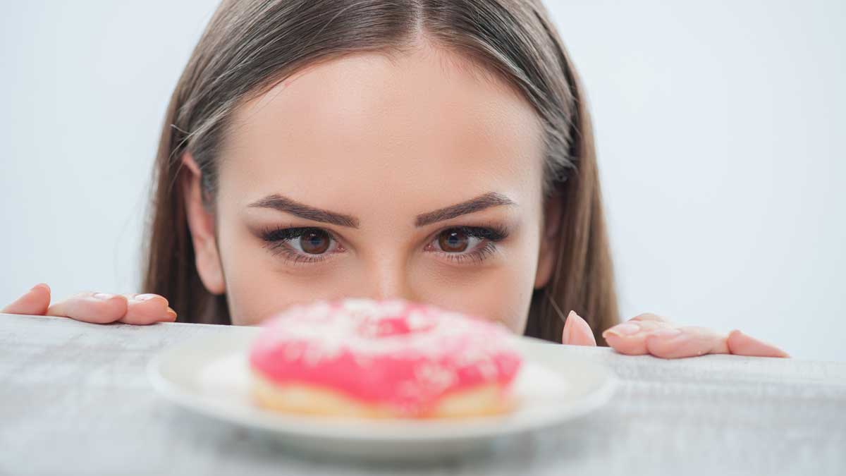 девушка смотрит аппетитно на сладкий пончик