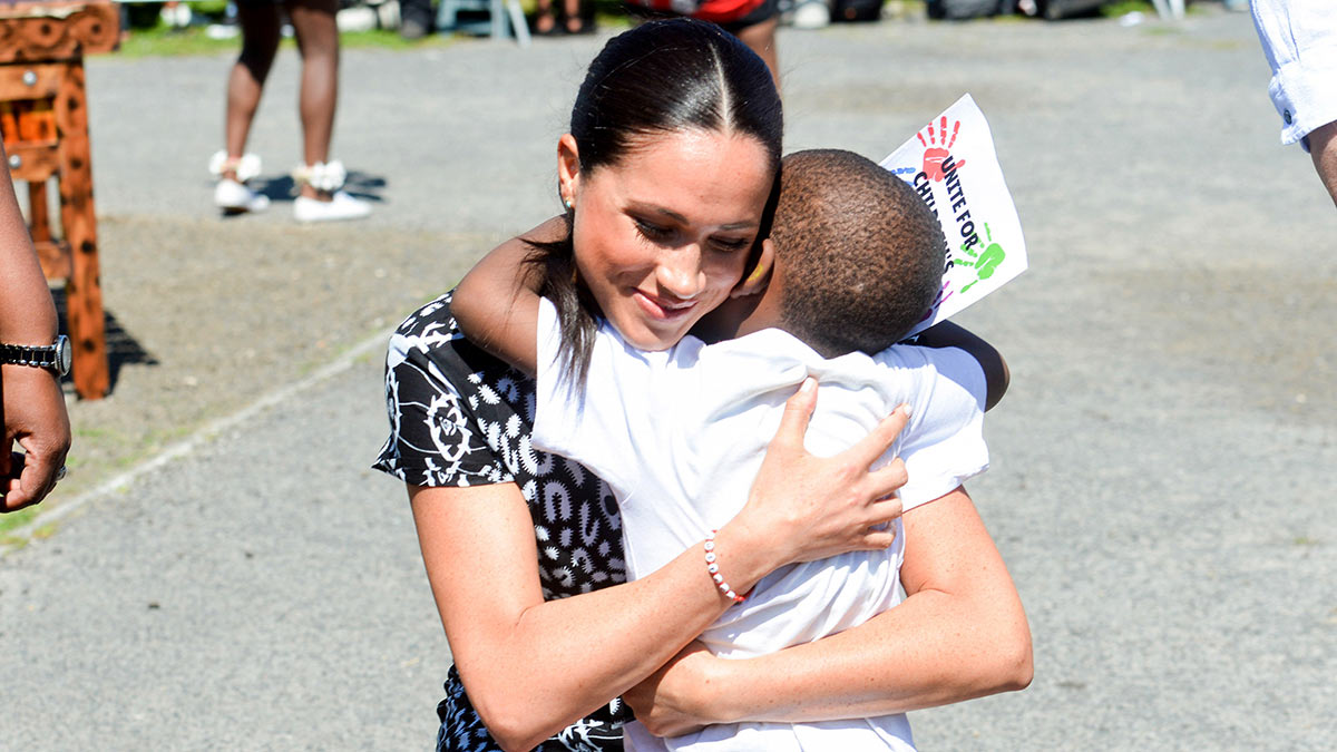 Меган Маркл обнимает ребенка во время посещения городка Ньянга, Кейптаун, Южная Африка