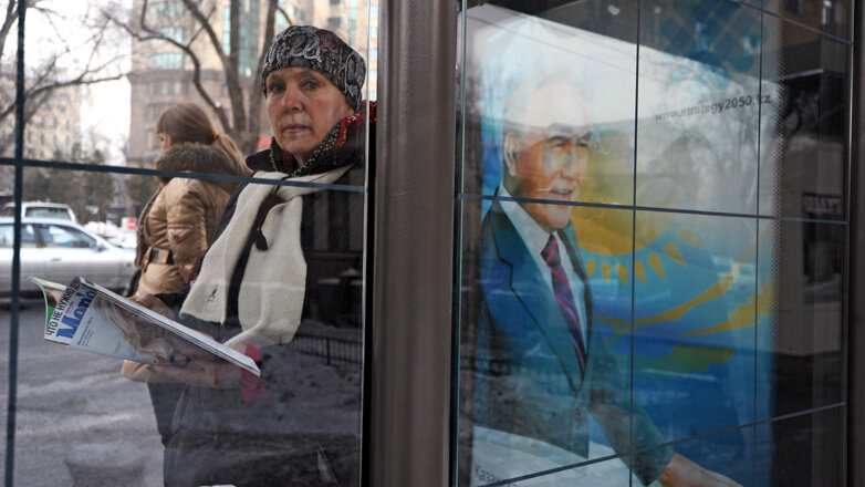 женщина рядом с портретом Нурсултана Назарбаева