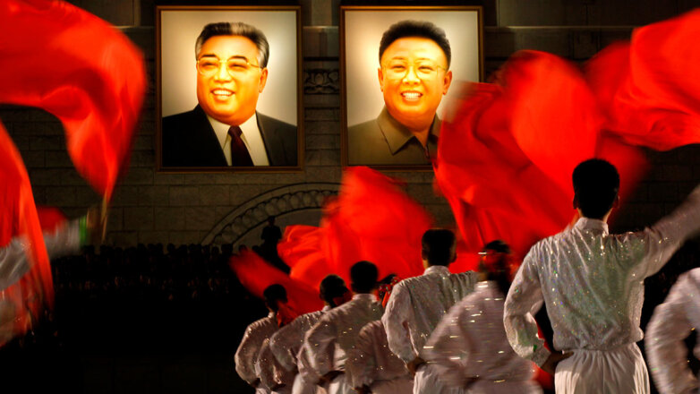 Cеверокорейские танцоры перед портретами Ким Ир Сена и Ким Чен Ира
