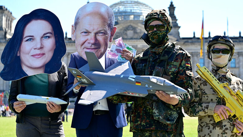 Активисты в масках Анналены Бербок и Олафа Шольца держат модель истребителя F-35