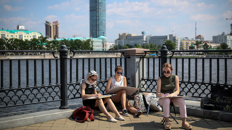 Девушки рисуют на берегу городского пруда напротив небоскреба "Высоцкий"