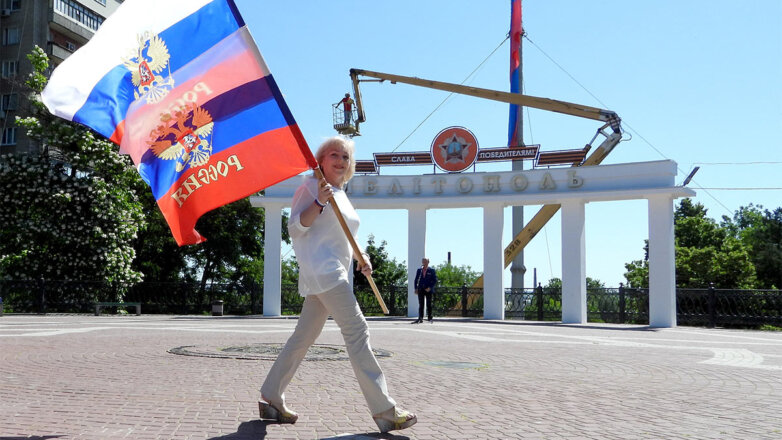 Мелитополь, Запорожская область. Женщина с флагами России на одной из улиц города.