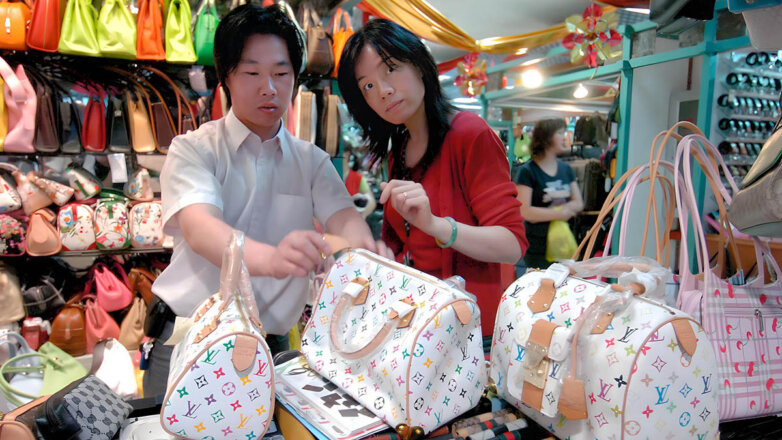 Женщина, выбирающая поддельную дизайнерскую сумочку в новом торговом центре Silk Street в Пекине