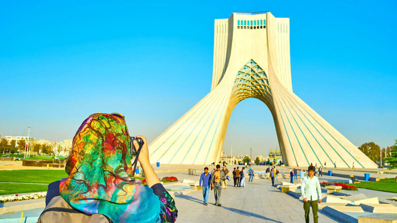 Туристка фотографирует башню Азади в Тегеране