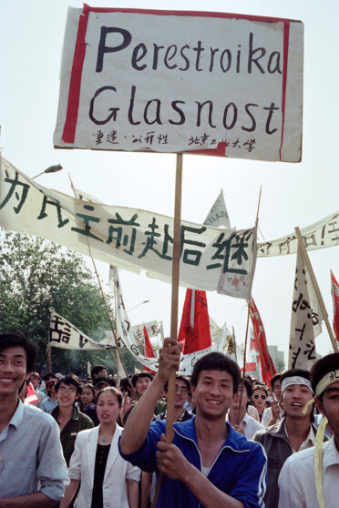 Студенты на митинге в Пекине размахивают табличкой с надписью "Перестройка, гласность"