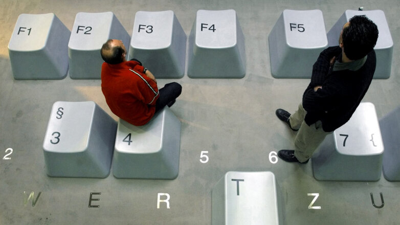Мужчины сидят на макете компьютерной клавиатуры