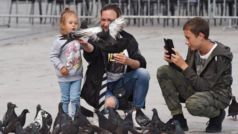 Женщина с детьми кормит голубей