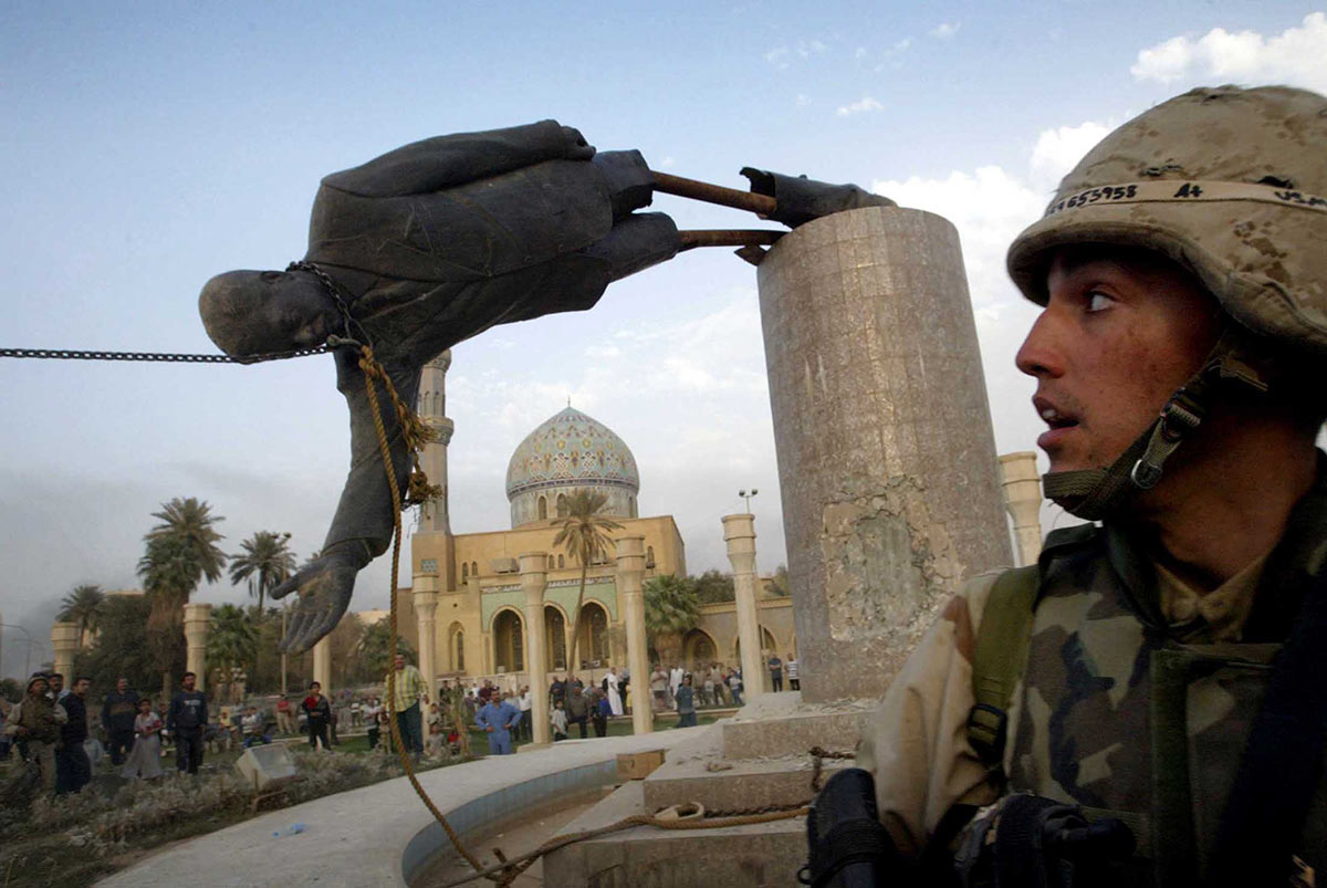 Штурмовик Корпуса морской пехоты США наблюдает за падением статуи президента Ирака Саддама Хусейна