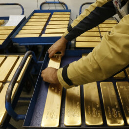 Сотрудник укладывает слитки 99,99% чистого золота на тележку на заводе цветных металлов