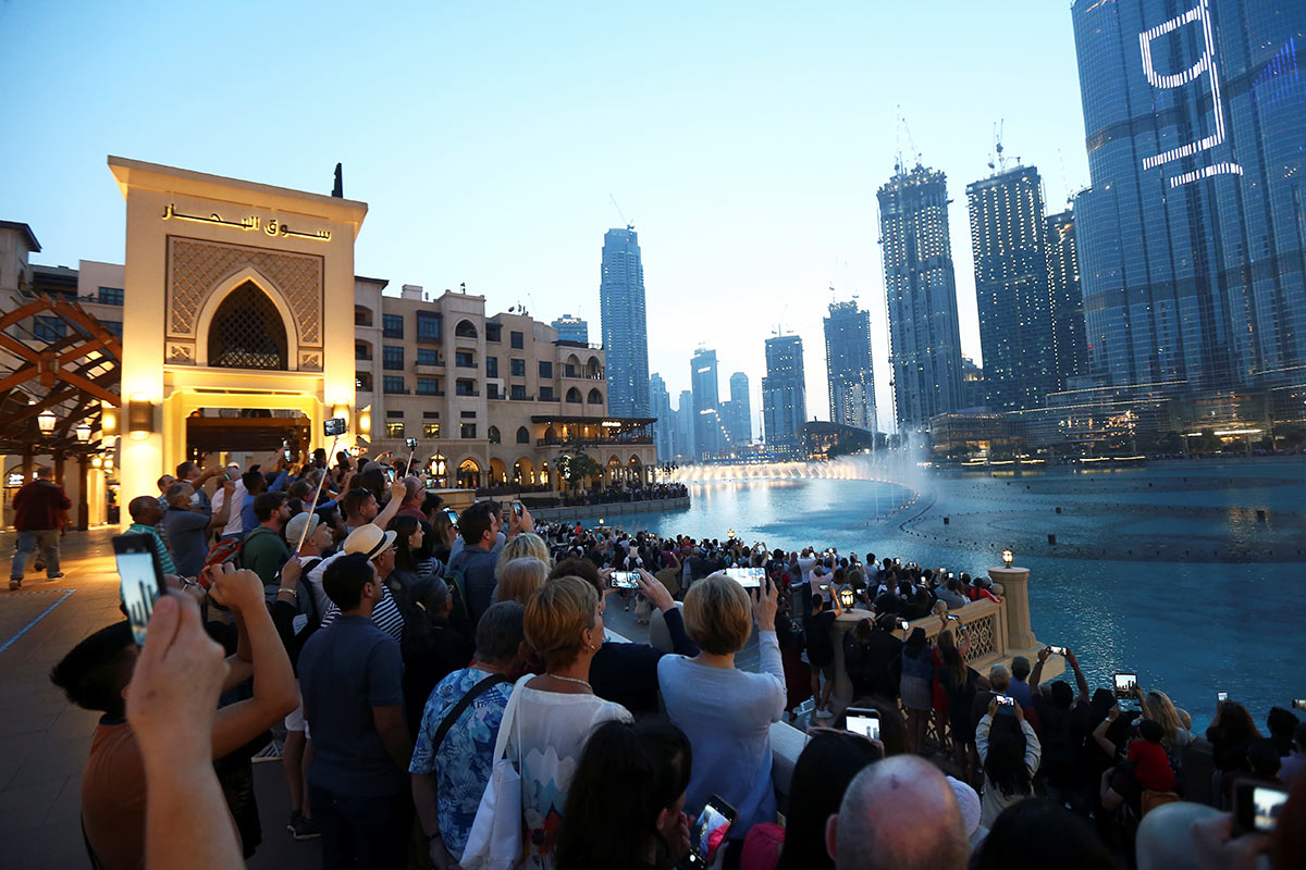 Туристы смотрят шоу фонтанов около башни Бурдж-Халифа в Дубае