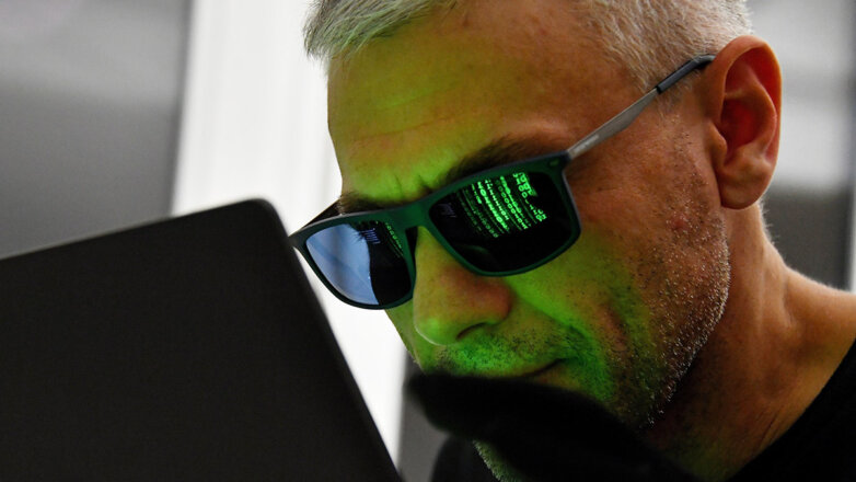 Мужчина в темных очках у компьютера.