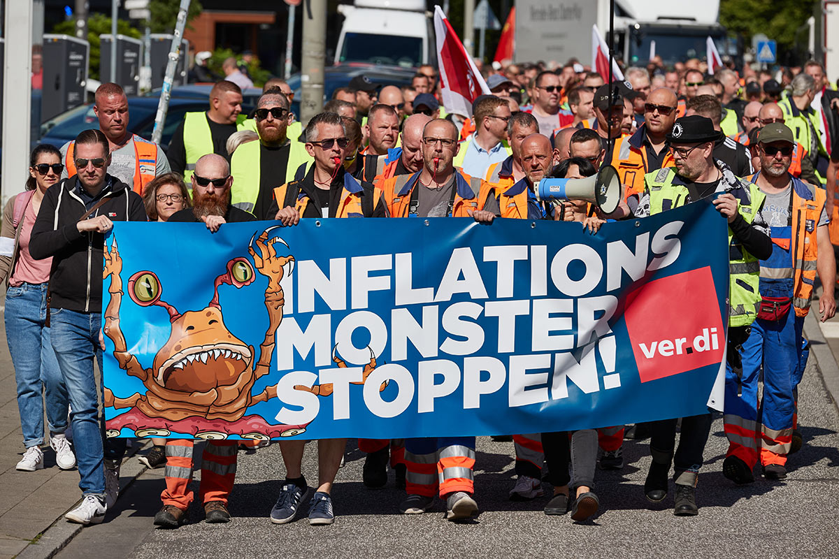 Докеры несут плакат с надписью "Остановите инфляционного монстра!" на митинге по поводу заработной платы в Германии