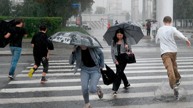 Люди перебегают улицу по пешеходному переходу во время дождя в Москве