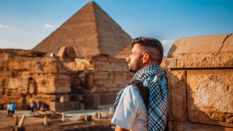 Турист рядом с египетской пирамидой