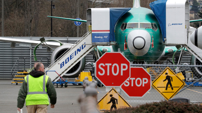 Рабочий компании Boeing идет перед самолетом 737 MAX в Рентоне