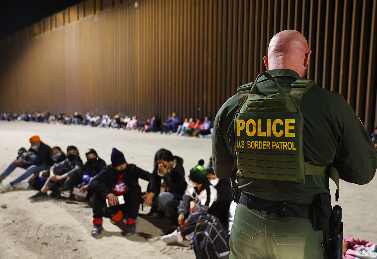 Сотрудник пограничного патруля США проверяет паспорта иммигрантов