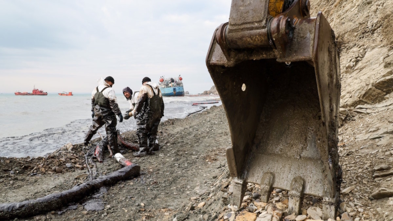 Волонтёры во время ликвидации последствий выброса нефтепродуктов на побережье Чёрного моря. На дальнем плане - танкер 